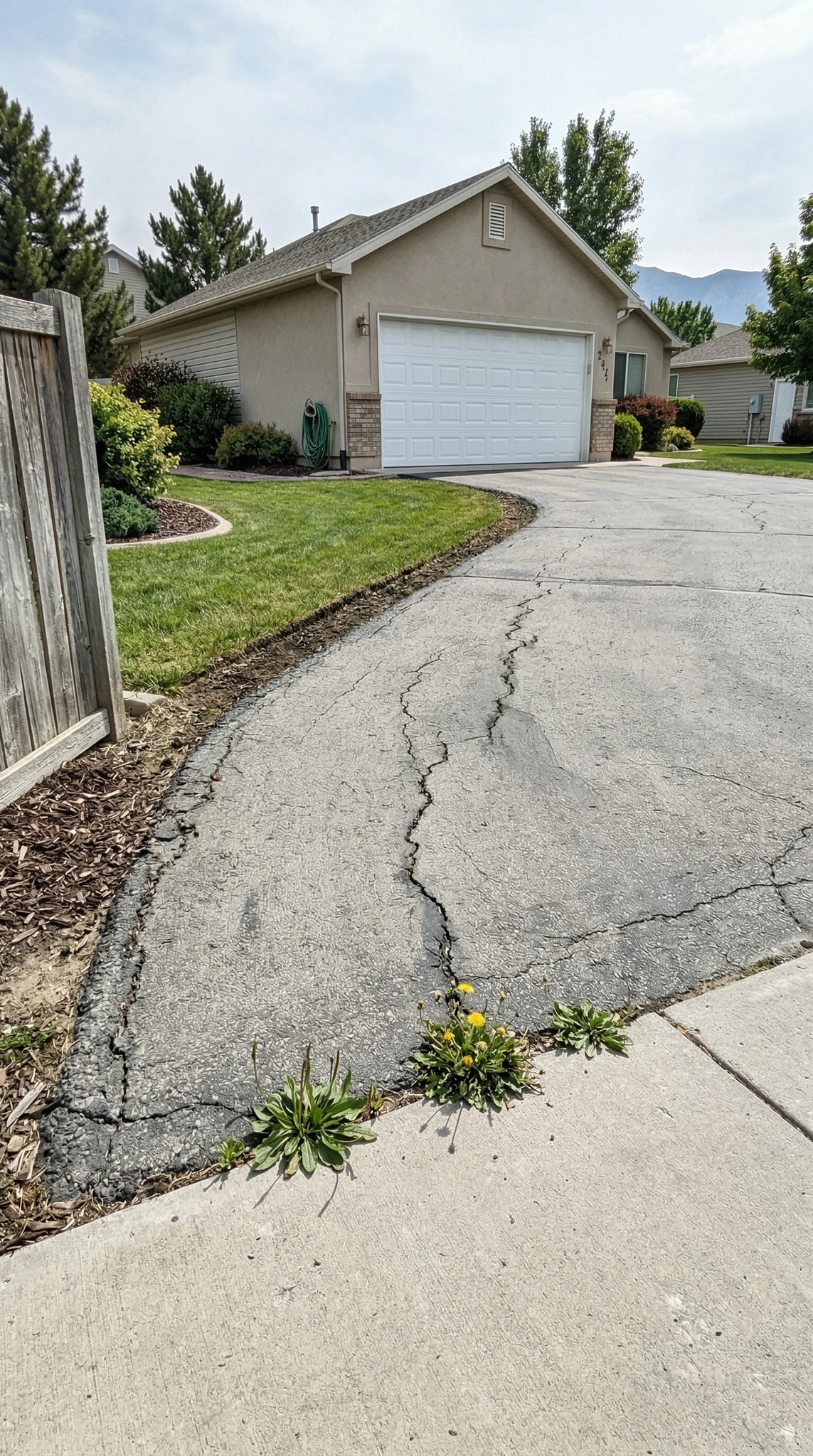 Cracked old asphalt driveway before D&M Paving resurfaced it