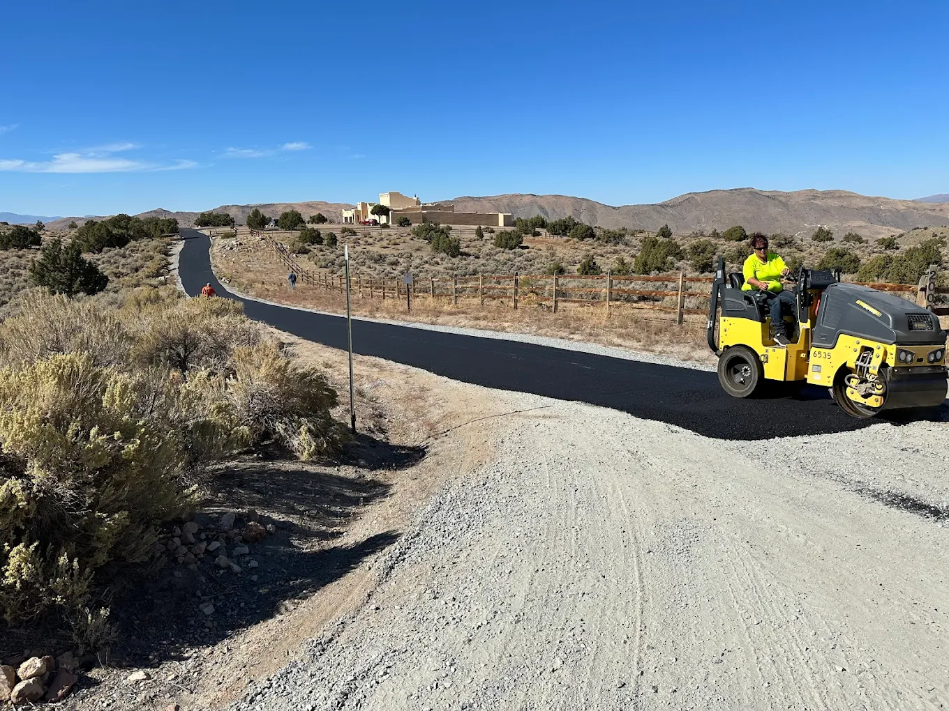 Chip-sealed private road being compacted with a roller